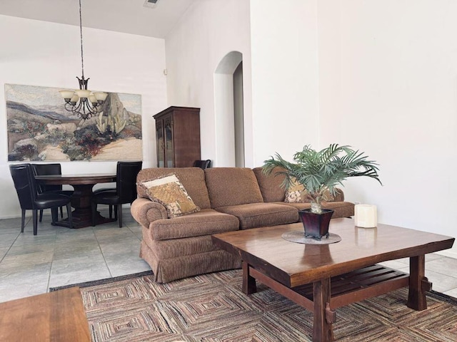 living room with tile patterned flooring, a towering ceiling, and an inviting chandelier