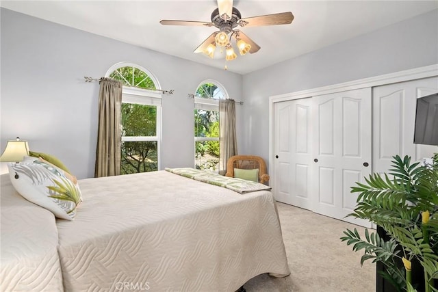 bedroom with ceiling fan, a closet, and light carpet