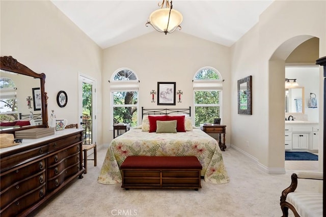 bedroom with high vaulted ceiling, light colored carpet, sink, and connected bathroom