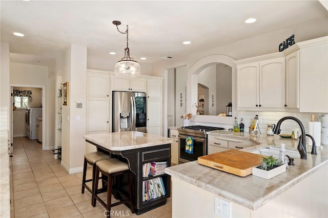 kitchen featuring white cabinetry, stainless steel appliances, tasteful backsplash, decorative light fixtures, and a kitchen island