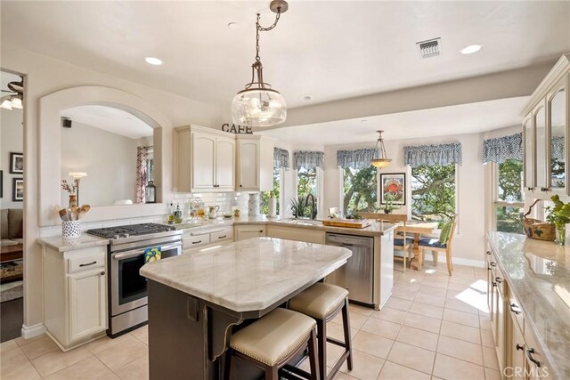 14600 El Monte Rd, Atascadero, CA 93422 - kitchen with stainless steel appliances, a peninsula, light tile patterned floors, a kitchen island, and healthy amount of natural light