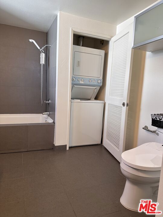 bathroom featuring stacked washer and clothes dryer and tiled shower / bath