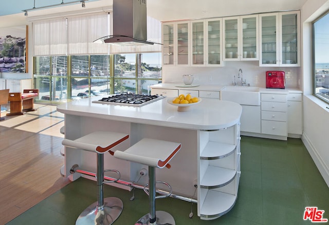 kitchen with white cabinets, plenty of natural light, and wall chimney range hood