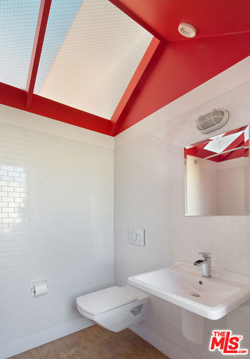 bathroom featuring hardwood / wood-style flooring, sink, vaulted ceiling, and toilet