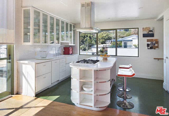 kitchen featuring tasteful backsplash, island range hood, sink, white cabinets, and hardwood / wood-style floors