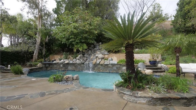 view of swimming pool with pool water feature and a patio