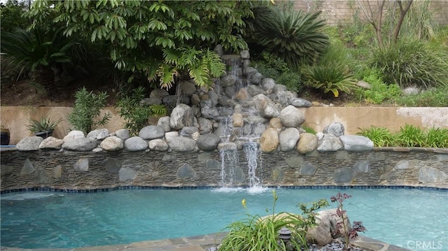 view of swimming pool with pool water feature