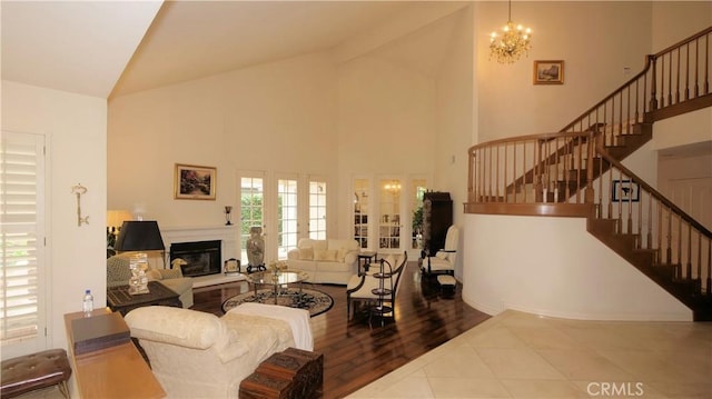 living room featuring hardwood / wood-style floors, french doors, high vaulted ceiling, and an inviting chandelier