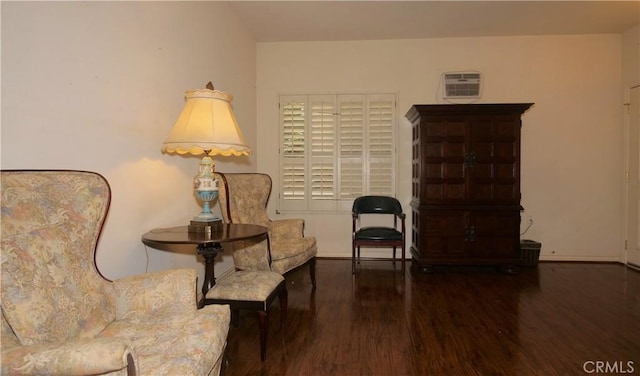 sitting room featuring dark wood-type flooring and an AC wall unit