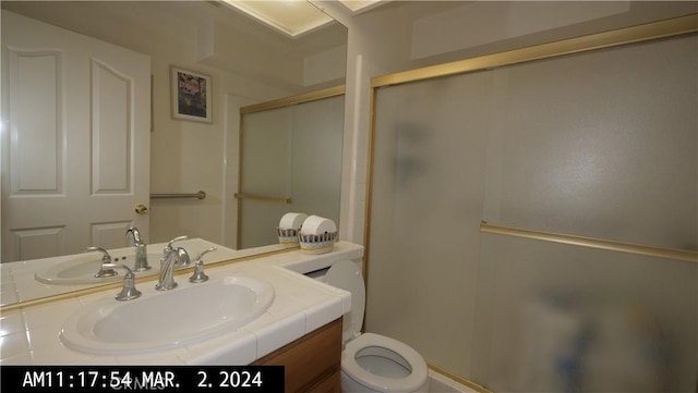 bathroom featuring vanity, toilet, and a shower with door