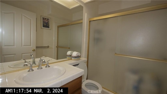 bathroom with vanity, a shower with door, and toilet