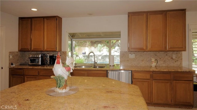 kitchen with dishwasher, light stone countertops, decorative backsplash, and sink