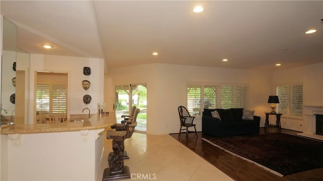 kitchen with sink, light stone counters, light tile patterned floors, a kitchen breakfast bar, and kitchen peninsula