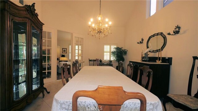 tiled dining space with french doors, a high ceiling, and a notable chandelier