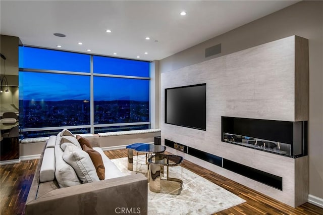 living room featuring visible vents, a tiled fireplace, wood finished floors, and recessed lighting