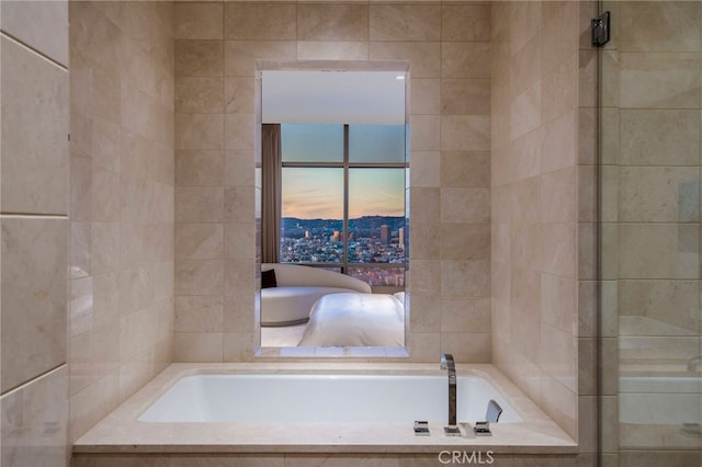 bathroom featuring tiled tub and tile walls