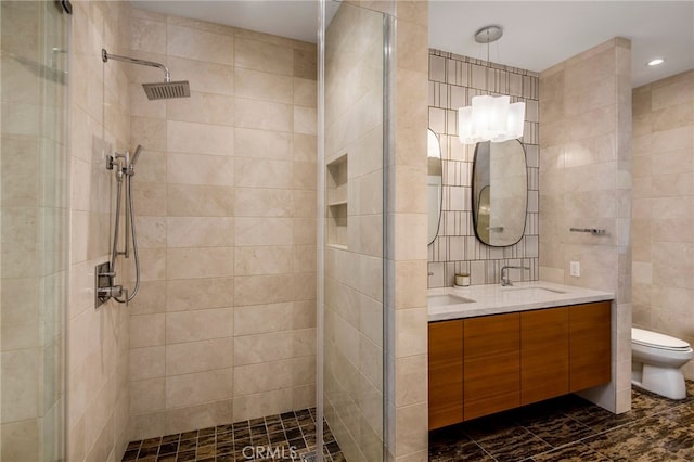 bathroom featuring tile walls, vanity, toilet, and a tile shower