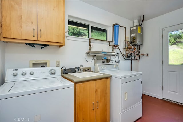 clothes washing area featuring sink, washer and dryer, water heater, and cabinets