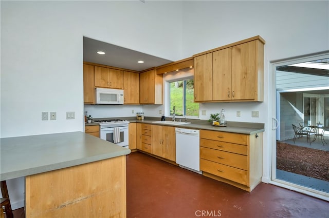 kitchen featuring sink, kitchen peninsula, and white appliances