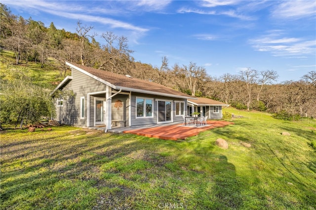 back of house featuring a patio, a wooden deck, and a lawn