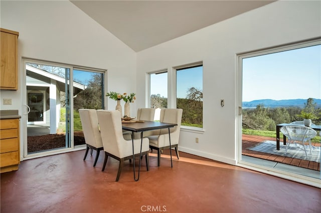 dining room featuring a mountain view, a healthy amount of sunlight, and vaulted ceiling