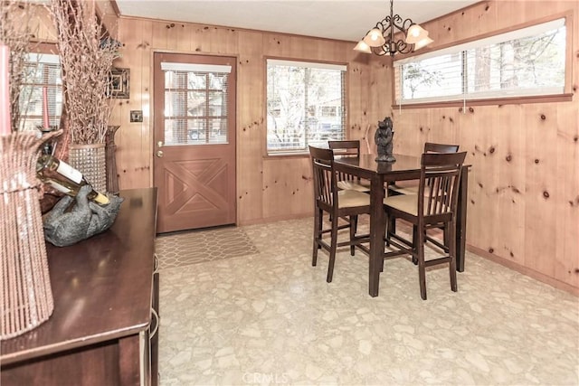 dining space with wood walls and an inviting chandelier