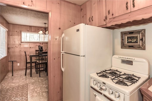 kitchen with wood walls, light brown cabinets, white appliances, and a notable chandelier