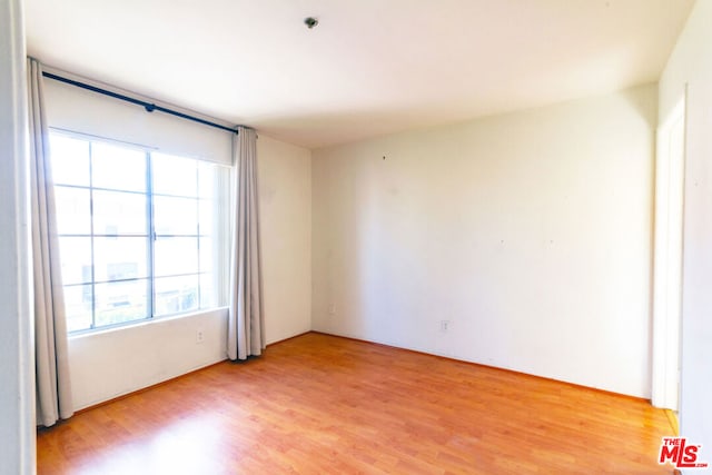 spare room featuring a wealth of natural light and hardwood / wood-style floors