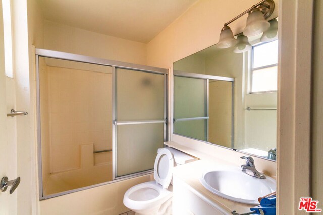 full bathroom with vanity, bath / shower combo with glass door, and toilet