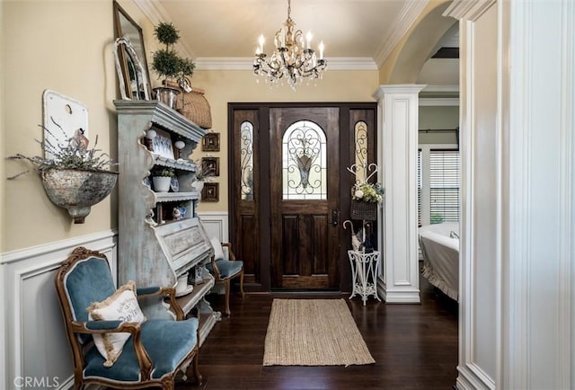 foyer entrance with dark wood finished floors, a wainscoted wall, an inviting chandelier, arched walkways, and crown molding