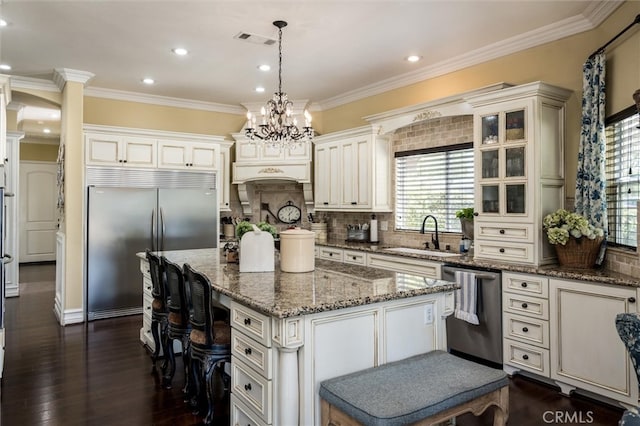 kitchen featuring a center island, dark wood-type flooring, sink, appliances with stainless steel finishes, and decorative light fixtures