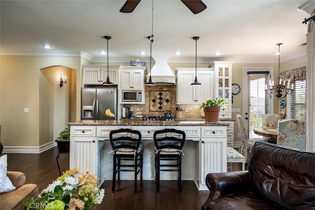 kitchen with hanging light fixtures, appliances with stainless steel finishes, a center island, a breakfast bar area, and dark hardwood / wood-style flooring