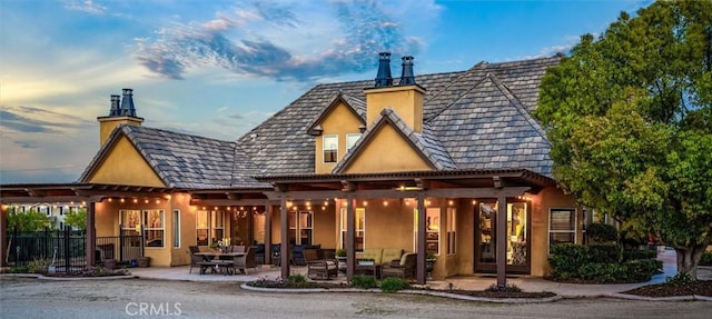 rear view of house featuring outdoor lounge area, a patio area, stucco siding, and fence