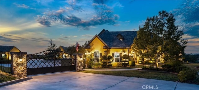 exterior space with concrete driveway, a gate, and stucco siding