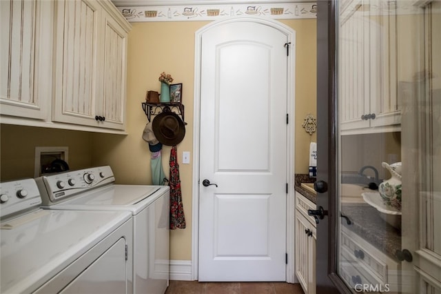 laundry room with dark tile patterned floors, cabinets, and washer and clothes dryer