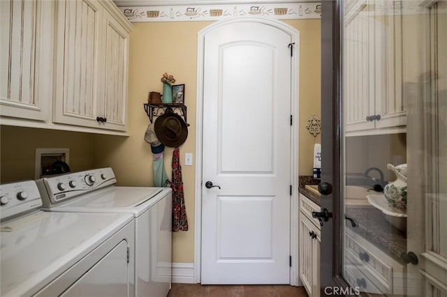 washroom featuring separate washer and dryer, cabinet space, and dark tile patterned floors