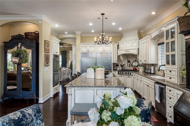 kitchen featuring a center island, dark wood-type flooring, sink, appliances with stainless steel finishes, and decorative light fixtures