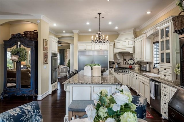 kitchen featuring a center island, a sink, an inviting chandelier, stone countertops, and appliances with stainless steel finishes