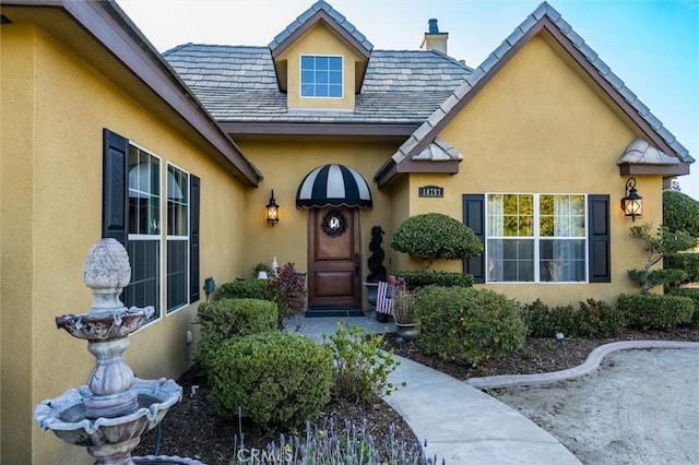 doorway to property featuring a chimney and stucco siding