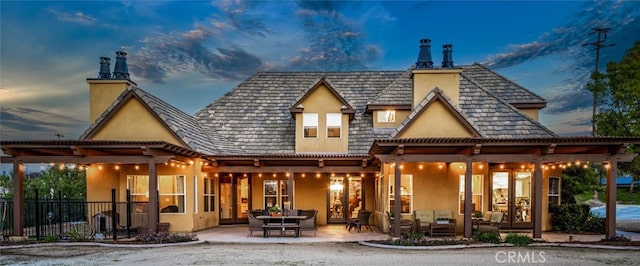 back house at dusk with an outdoor living space and a patio area