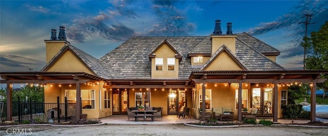 rear view of house with stucco siding, fence, a patio, and an outdoor hangout area