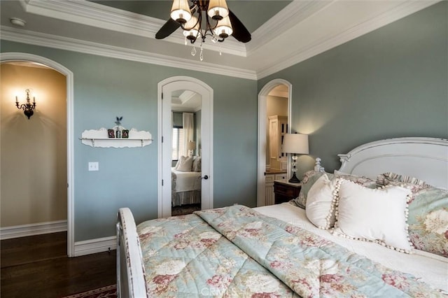 bedroom with arched walkways, dark wood-style flooring, a ceiling fan, crown molding, and a raised ceiling