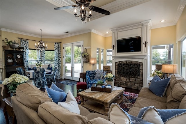 living room featuring ceiling fan with notable chandelier, crown molding, a fireplace, french doors, and hardwood / wood-style flooring