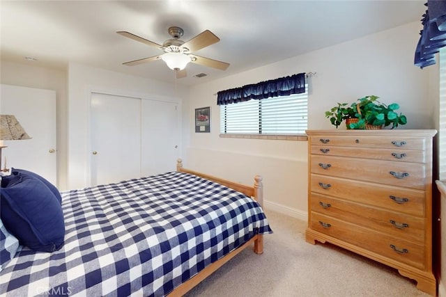 bedroom featuring light carpet, ceiling fan, and a closet