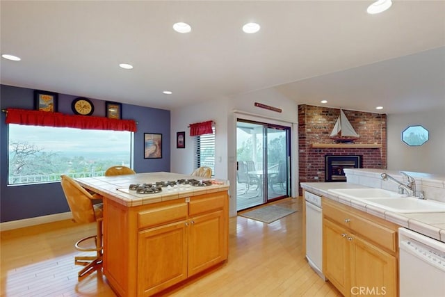 kitchen featuring tile countertops, a center island, sink, white appliances, and light hardwood / wood-style flooring