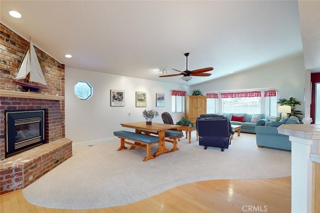 living room featuring ceiling fan, vaulted ceiling, a fireplace, and hardwood / wood-style flooring