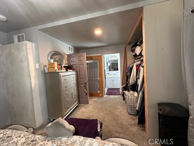 bedroom featuring light carpet, a closet, and ensuite bathroom