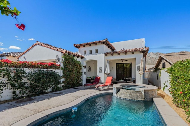 back of house with ceiling fan, a swimming pool with hot tub, and a patio area