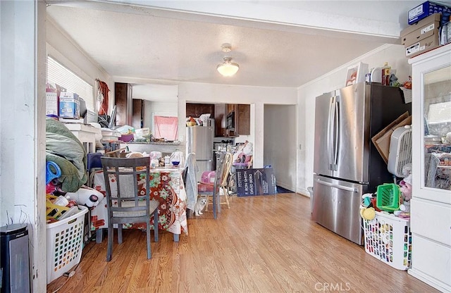 kitchen with light hardwood / wood-style floors, ornamental molding, and stainless steel refrigerator