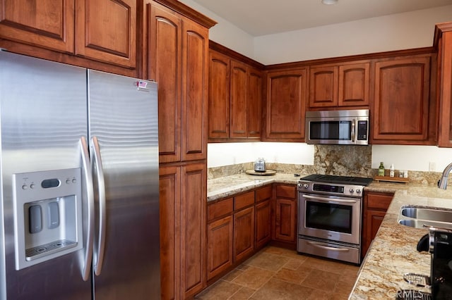 kitchen with light stone counters, sink, decorative backsplash, and appliances with stainless steel finishes